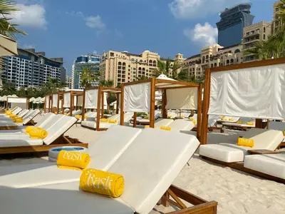 a row of beds on a beach with buildings at Fairmont North 2BR Full Sea View in Dubai