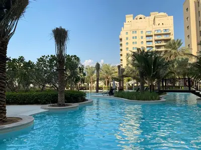 a large swimming pool with palm trees and buildings at Fairmont North 2BR Full Sea View in Dubai