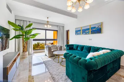 a living room with a green couch and a table at Fairmont North 2BR Full Sea View in Dubai