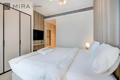 a white bed in a room with a television at Mira Holiday Homes - Lovely 2 BDR with Sea View in Dubai