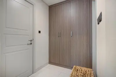 a hallway with a door and a wooden cabinet at Arabian-Inspired 1BR - Polo Residence Near Burj in Dubai