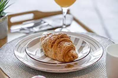 a pastry on a plate on a table with a glass of wine at Livin' Holidays - Luxury studio with Bay view in Dubai