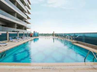 a large swimming pool with chairs and a building at Charming Studio Escape With Unobstructed City View in Dubai