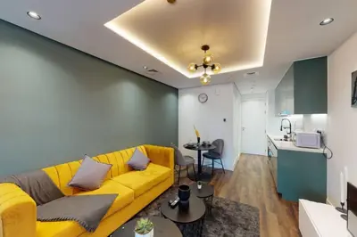 a living room with a yellow couch and a kitchen at Shiny & Fresh - Studio with Lake View - JLT in Dubai