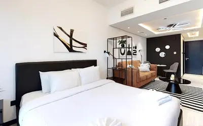 a bedroom with a large white bed and a living room at Earthy & Sharp - Studio with Lake View - JLT in Dubai