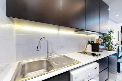 a kitchen with a stainless steel sink and black cabinets at Earthy & Sharp - Studio with Lake View - JLT in Dubai