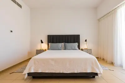a white bedroom with a large bed and two lamps at JBR Full Sea View Apartment 1 BR in Dubai