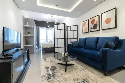 a living room with a blue couch and a tv at Classy and Bright - Studio - JLT in Dubai