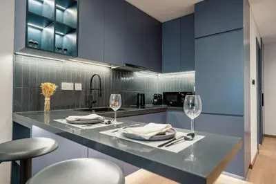 a kitchen with blue cabinets and a counter with wine glasses at Stylish and Sleek - Studio - JLT in Dubai