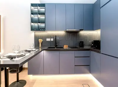 a kitchen with blue cabinets and a table with wine glasses at Stylish and Sleek - Studio - JLT in Dubai