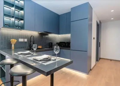 a kitchen with blue cabinets and a table with wine glasses at Stylish and Sleek - Studio - JLT in Dubai