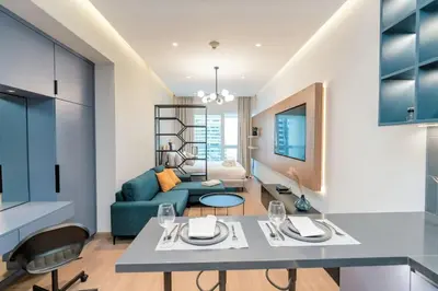 a kitchen and living room with a blue couch at Stylish and Sleek - Studio - JLT in Dubai