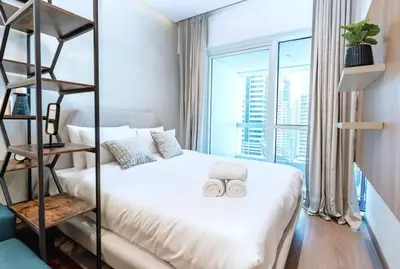 a bedroom with a white bed with two towels on it at Stylish and Sleek - Studio - JLT in Dubai