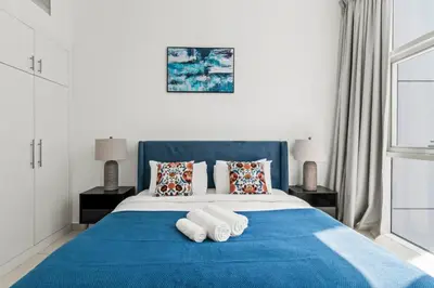 a bedroom with a blue bed with towels on it at Lavish 2BR with Charming Marina View in Dubai