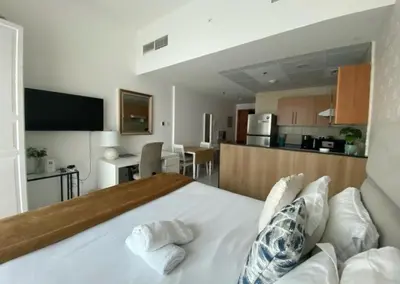 a bedroom with a large white bed and a kitchen at Spontaneous Sea View and High floor Studio Apartment in Dubai