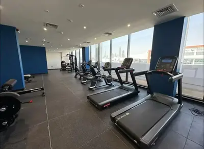 a gym with rows of treadmills and elliptical machines at Dubai Galaxy in Azizi Riviera Luxury Studio in Dubai