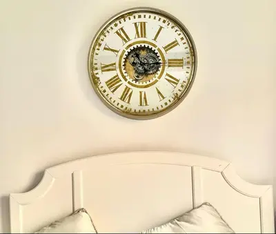 a gold clock on a wall above a white shelf at Dubai Galaxy in Azizi Riviera Luxury Studio in Dubai