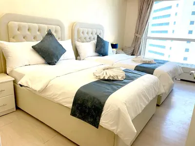 two twin beds in a room with a window at ROYAL BEACH RESIDENCES 2 in Dubai