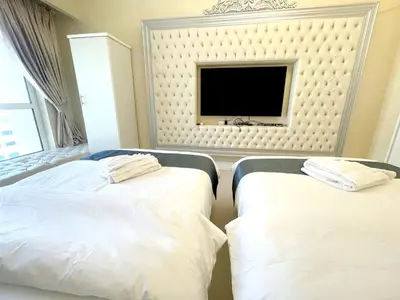 two beds in a hotel room with a flat screen tv at ROYAL BEACH RESIDENCES 2 in Dubai