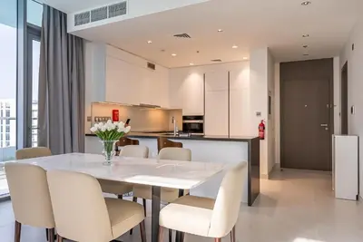 a kitchen and dining room with a white table and chairs at 3BDR with Maid Room I District One I Spacious and Cozy in Dubai