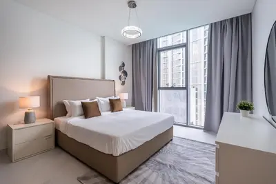 a bedroom with a bed and a large window at 3BDR with Maid Room I District One I Spacious and Cozy in Dubai