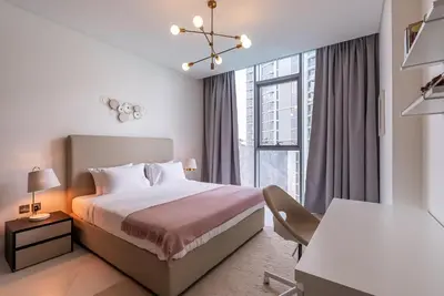 a bedroom with a bed and a desk and a window at 3BDR with Maid Room I District One I Spacious and Cozy in Dubai