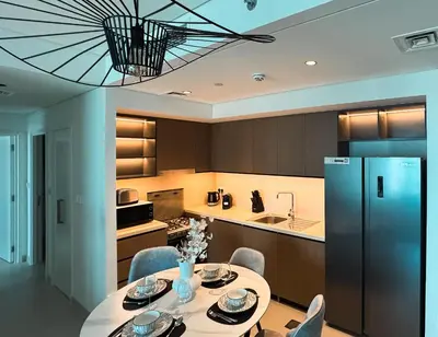 a kitchen with a table with chairs and a refrigerator at Burj Crown Luxury 2bedroom Balcony & View in Dubai