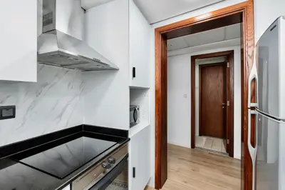a kitchen with white counters and a sink and a door at Next To Metro Unique 2bed Apt Wlarge Balcony in Dubai