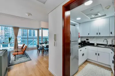 a kitchen with white cabinets and a dining room at Next To Metro Unique 2bed Apt Wlarge Balcony in Dubai