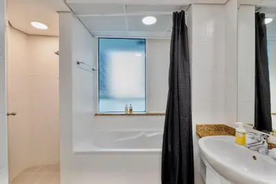 a white bathroom with a tub and a sink at Next To Metro Unique 2bed Apt Wlarge Balcony in Dubai