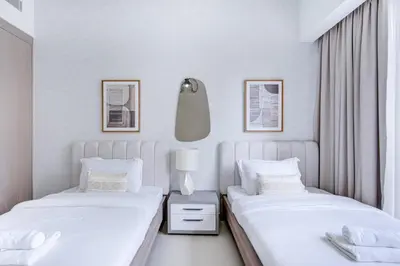 two beds in a bedroom with white walls at Brand New Luxurious 2BR ACT Towers Downtown in Dubai