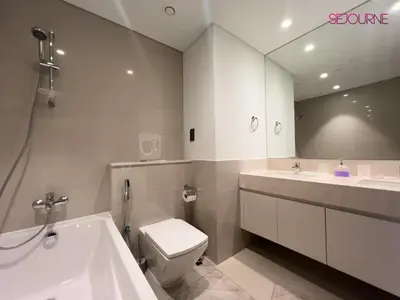 a bathroom with a tub and a toilet and a mirror at Brand New Luxurious 2BR ACT Towers Downtown in Dubai