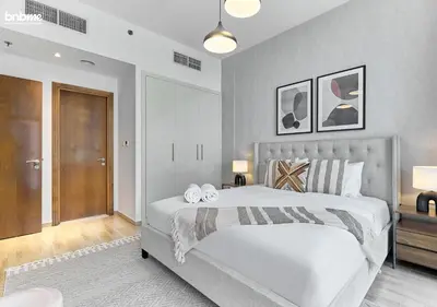 a bedroom with a large bed with two pillows on it at bnbme - Premium 1BR Apt Balcony Pool Gym Parking Near Dubai Mall & Burj Khalifa in Dubai