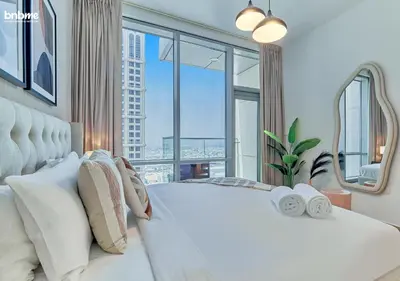 a bedroom with a large white bed with a large window at bnbme - Premium 1BR Apt Balcony Pool Gym Parking Near Dubai Mall & Burj Khalifa in Dubai