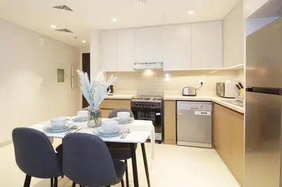 a kitchen with a table and chairs and a kitchen with white cabinets at Elegant Waterfront 1BHK in Dubai Creek Harbour in Dubai