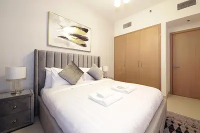 a bedroom with a large white bed with a wooden cabinet at Elegant Waterfront 1BHK in Dubai Creek Harbour in Dubai