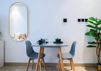 a dining room with a table and chairs and a mirror at HAVN - Studio in MYKA, Near Meaisem City Center in Dubai