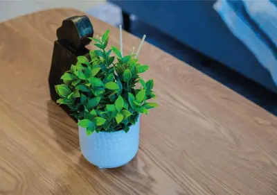 a small white vase with a plant on a table at HAVN - Studio in MYKA, Near Meaisem City Center in Dubai