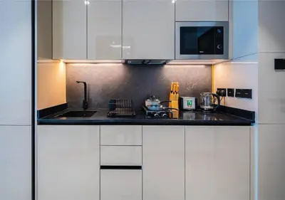 a kitchen with white cabinets and a black counter top at HAVN - Studio in MYKA, Near Meaisem City Center in Dubai