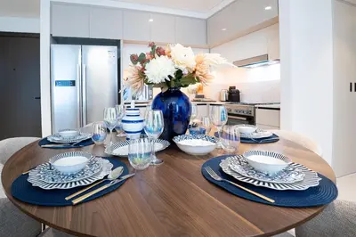 a dining room table with a blue vase with flowers at Veluxa - Luxe 2Bed with Private Beach in Dubai