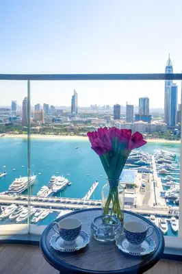 a table with two cups and a vase with flowers at Veluxa - Luxe 2Bed with Private Beach in Dubai
