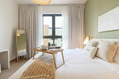 a bedroom with a bed with a table and a window at HiGuests - Coastal Chic Luxurious Retreat at Port de la Mer in Dubai