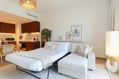a white bedroom with a bed and a couch at HiGuests - Coastal Chic Luxurious Retreat at Port de la Mer in Dubai
