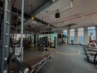 a gym with treadmills and people in the background at Naseem - Studio One Tower in Dubai