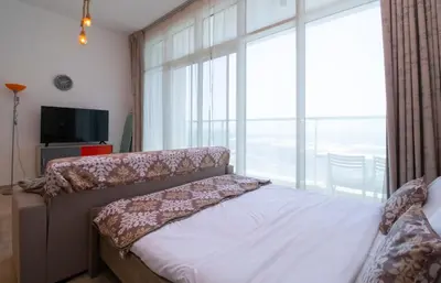 a bedroom with a bed and a large window at Naseem - Studio One Tower in Dubai