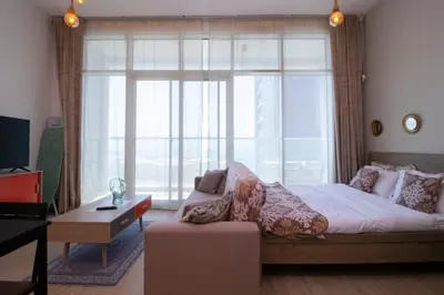 a living room with a bed and a large window at Naseem - Studio One Tower in Dubai