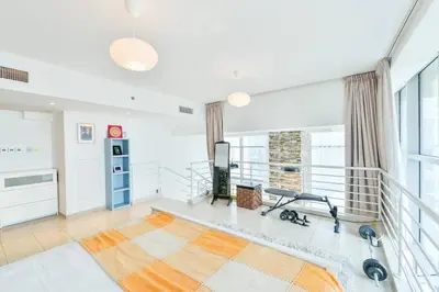 a living room with a treadmill and a gym at Jlt Spacious Corner Duplex Loft Panoramic Views in Dubai