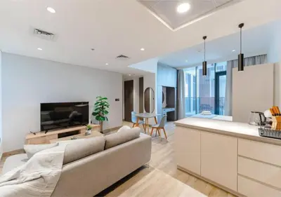 a living room with a large couch and a kitchen at HAVN - Studio Apartment in Chaimaa Avenue, JVC in Dubai