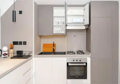 a kitchen with white cabinets and a stove top oven at HAVN - Studio Apartment in Chaimaa Avenue, JVC in Dubai
