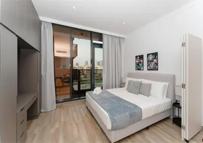 a bedroom with a white bed and a large window at HAVN - Studio Apartment in Chaimaa Avenue, JVC in Dubai